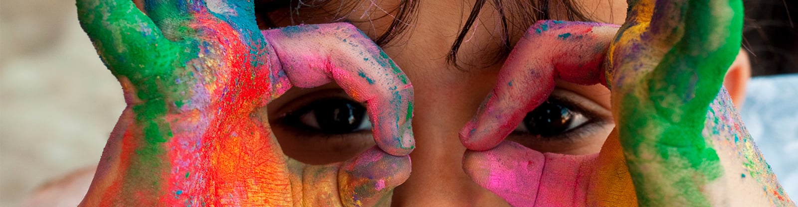 The child's painted hands frame the eyes