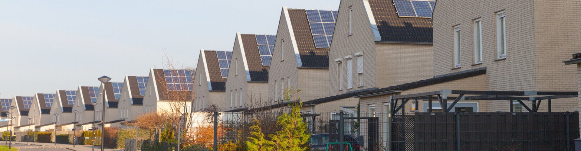 A housing estate of identical beige houses with solar panels on the roofs