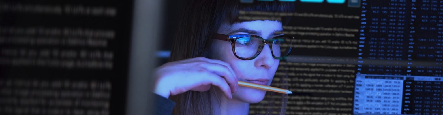 Business analyst looking at data on computer screens